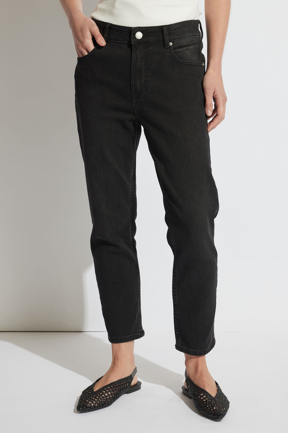 Woman wearing relaxed black girlfriend jeans paired with woven black slip-on flats, casual and stylish look.