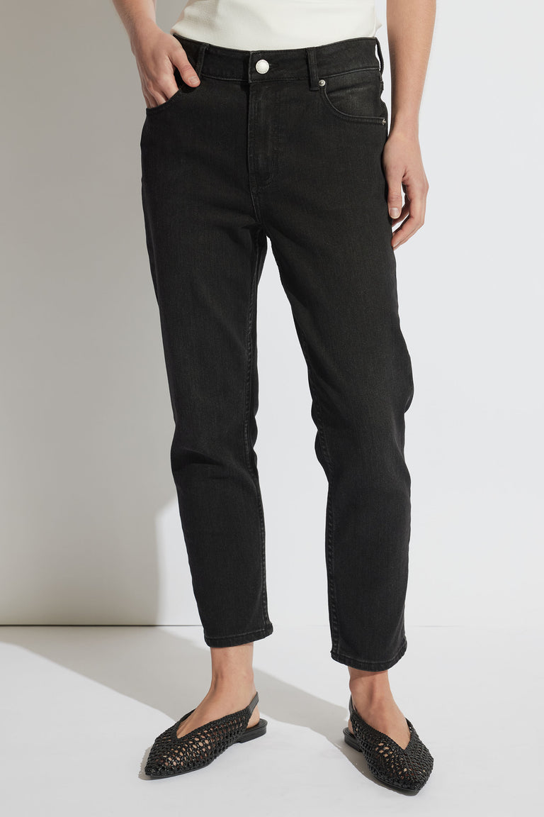 Woman wearing relaxed black girlfriend jeans paired with woven black slip-on flats, casual and stylish look.
