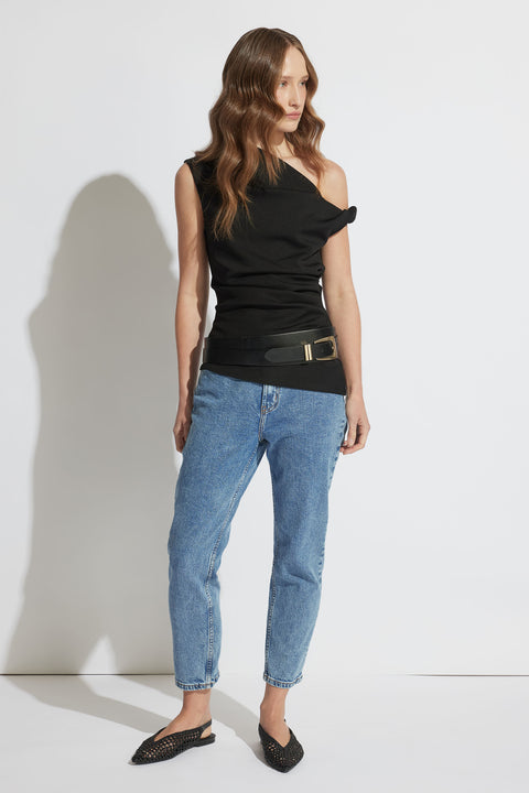 Woman wearing light blue relaxed-fit jeans with a black one-shoulder top and black pointed woven flats