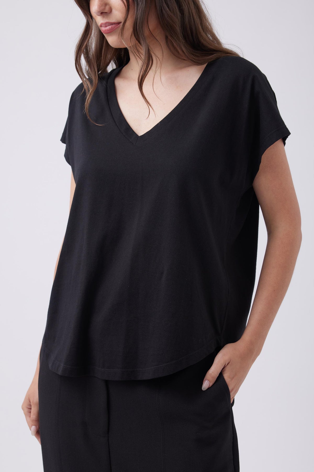 Woman wearing a soft black V-neck tee with relaxed short sleeves, styled casually with matching black pants.