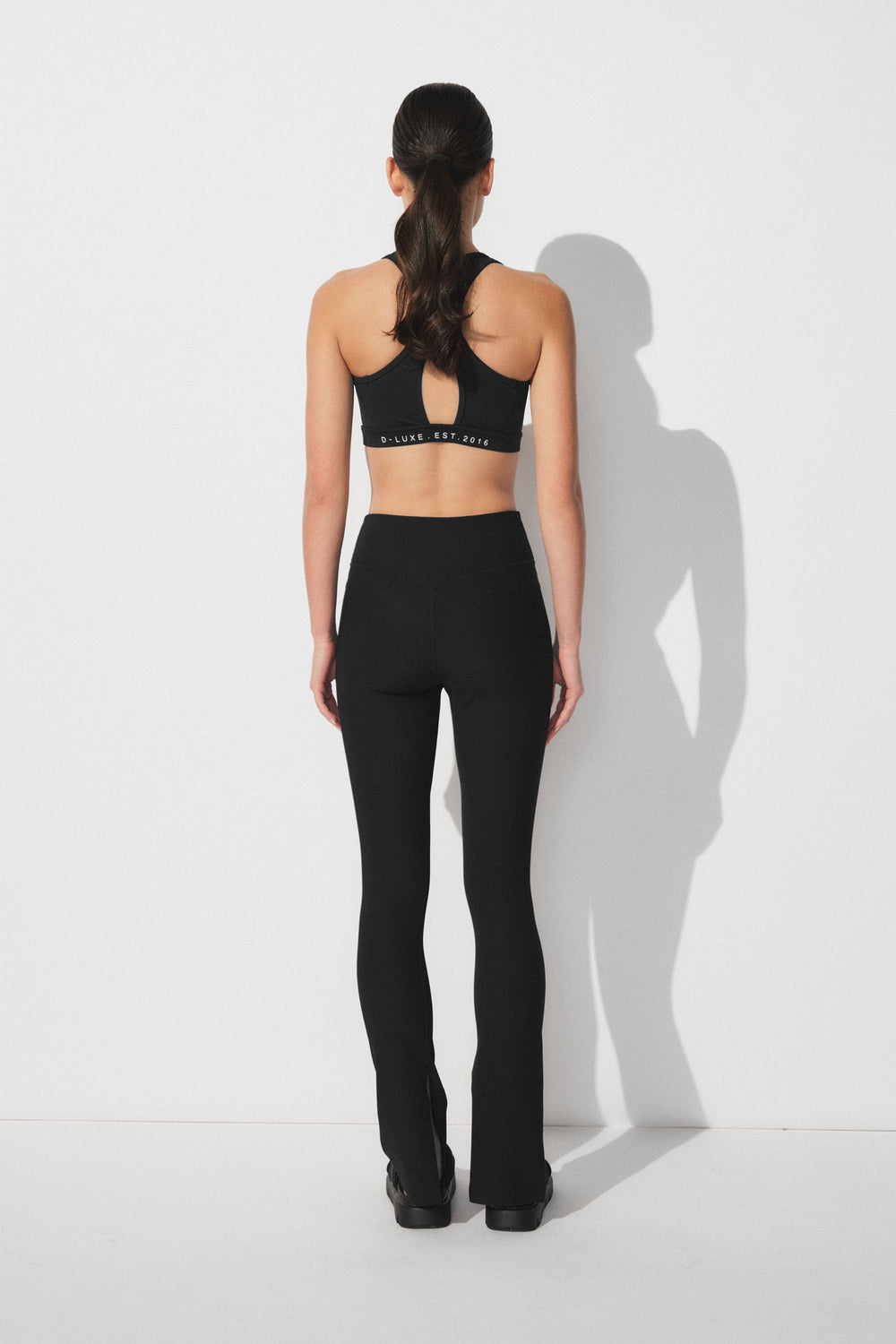Woman wearing black ribbed leggings with split hems paired with a sporty cropped tank top for a sleek active look