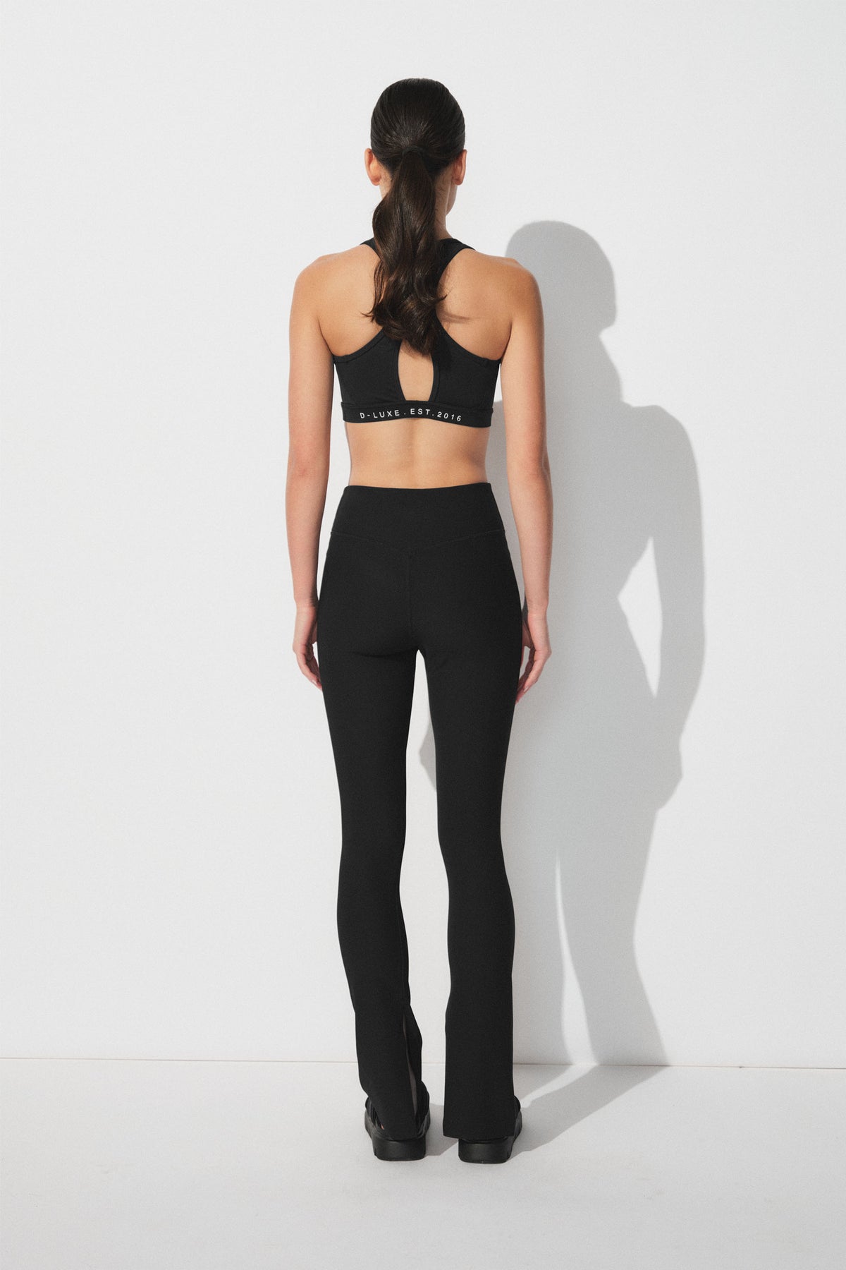 Woman wearing black ribbed leggings with split hems paired with a sporty cropped tank top for a sleek active look