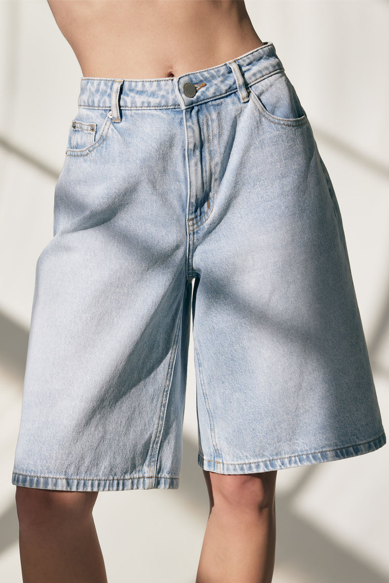 Light wash longline denim shorts with a relaxed fit and classic five-pocket styling for casual summer wear.