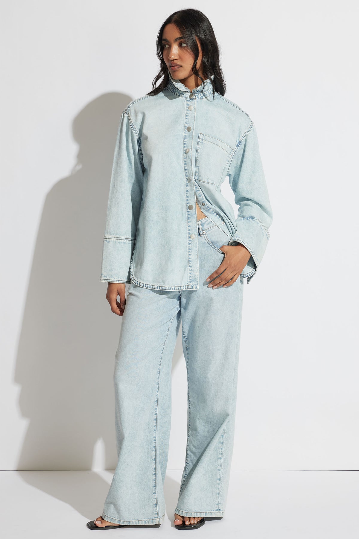 Woman wearing a relaxed light wash denim shirt with matching wide-leg jeans, styled for casual everyday wear