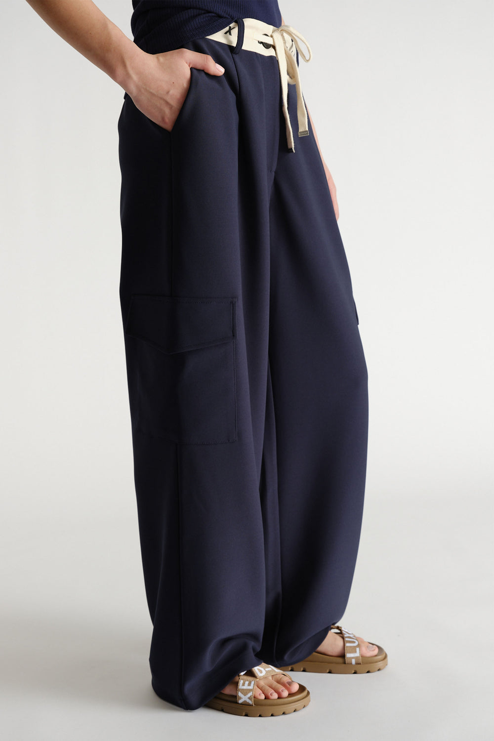 Navy wide-leg pants with contrast logo waistband and side cargo pockets styled with flat logo sandals