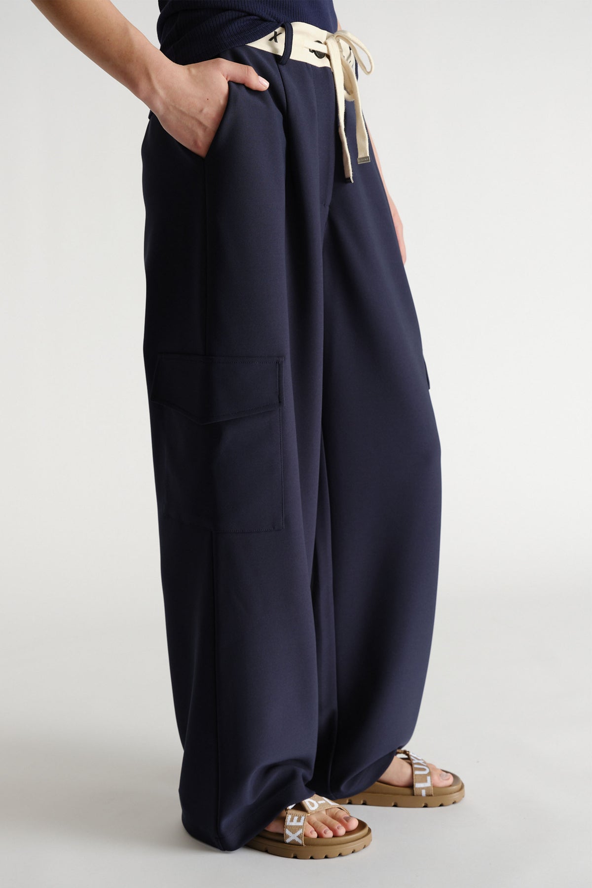 Navy wide-leg pants with contrast logo waistband and side cargo pockets styled with flat logo sandals