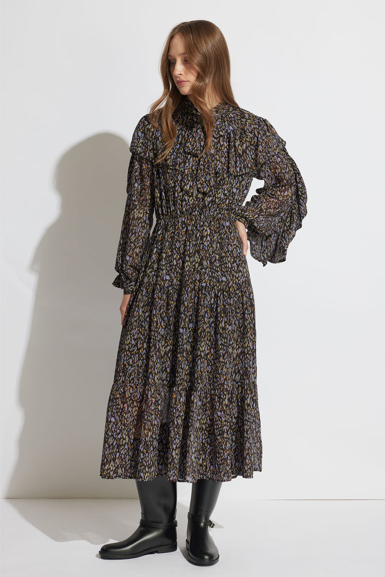 Woman wearing a flowy, patterned midi dress with ruffled sleeves and a tiered skirt paired with black boots