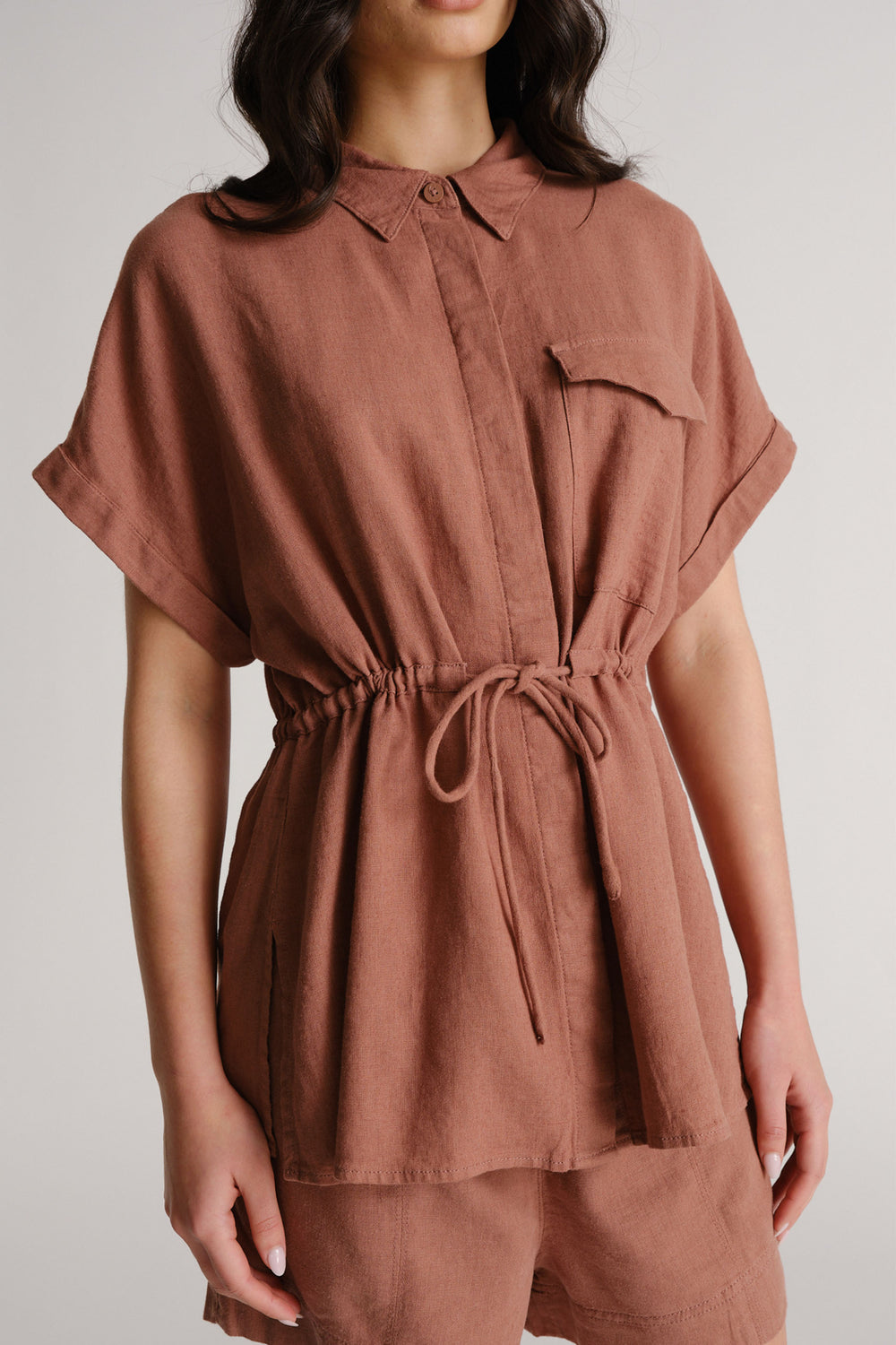 Woman wearing a terracotta linen blend shirt with a drawstring waist and matching shorts