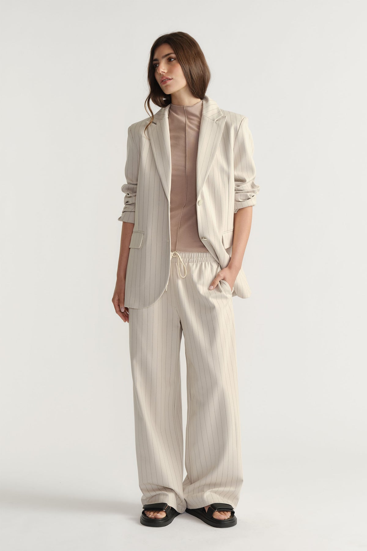 Woman wearing D-Luxe Pinstripe Pant in light beige with relaxed wide-leg fit paired with matching blazer by Decjuba Australian brand