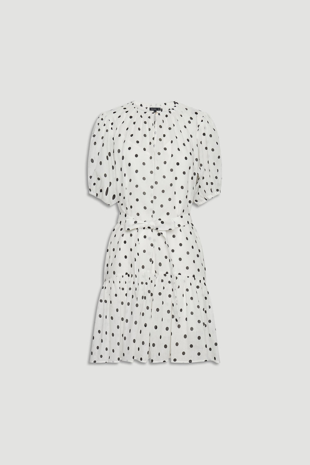White mini dress with black polka dots, featuring puff sleeves, a cinched waist, and a gathered tiered skirt.