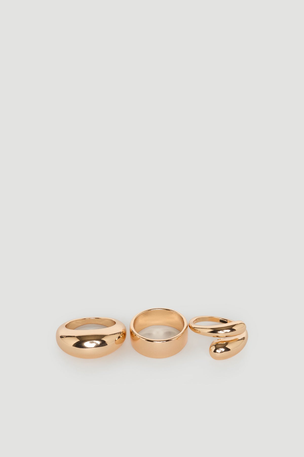Set of three polished gold rings featuring bold, smooth designs for versatile, everyday elegance.