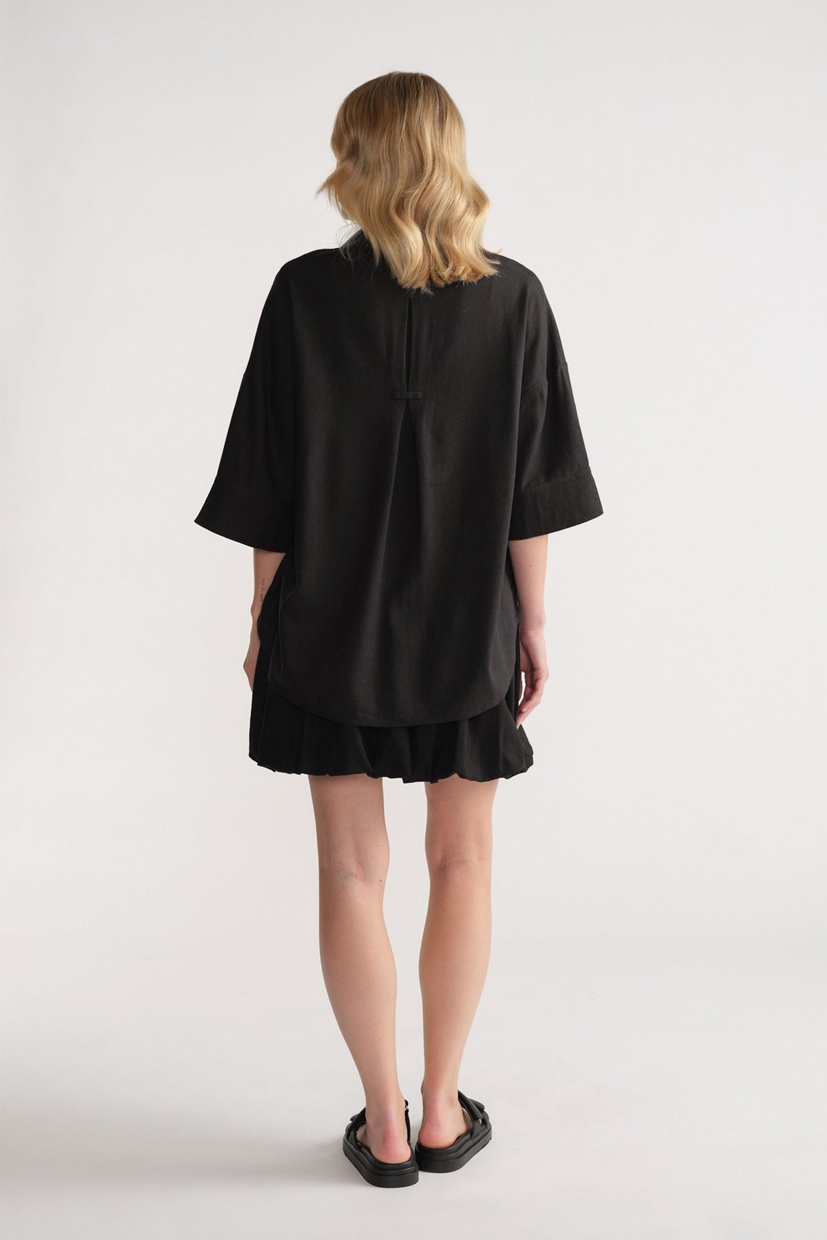 Back view of model wearing black D-Luxe Linen Blend 3/4 Shirt in gallery position 3, portrait orientation, lightweight linen blend.
