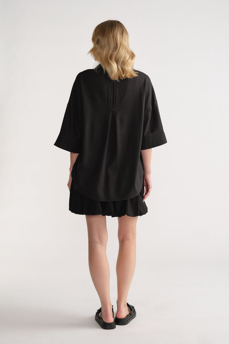 Back view of model wearing black D-Luxe Linen Blend 3/4 Shirt in gallery position 3, portrait orientation, lightweight linen blend.