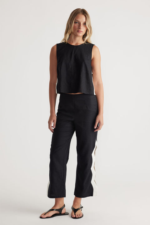 Front view portrait of model wearing black Tess Scallop Pant with contrast side splits and buttons closure, gallery position 1.