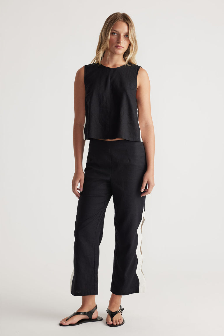 Front view portrait of model wearing black Tess Scallop Pant with contrast side splits and buttons closure, gallery position 1.