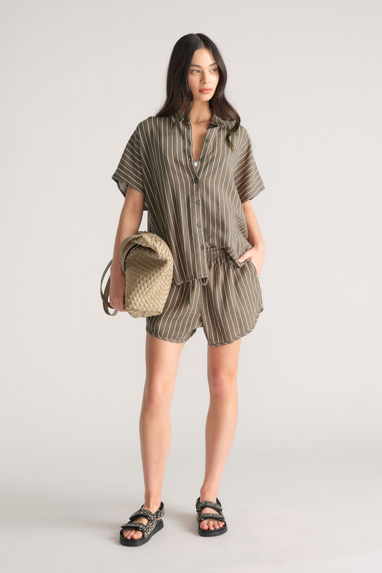 Model wearing D-Luxe Linen Blend Curve Short with striped top and woven bag, first gallery image, portrait orientation.