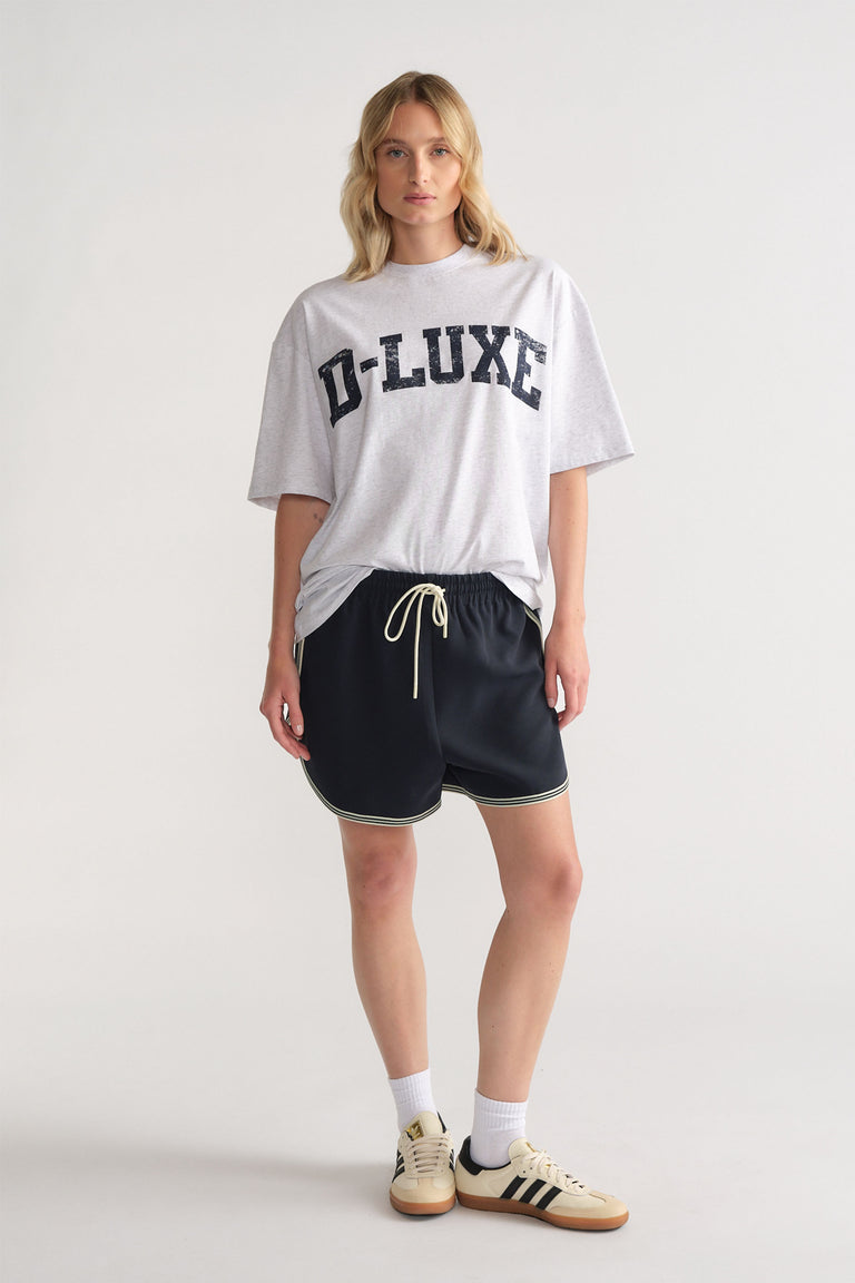 Woman wearing relaxed black racer stripe shorts with drawstring waist paired with a loose grey graphic tee