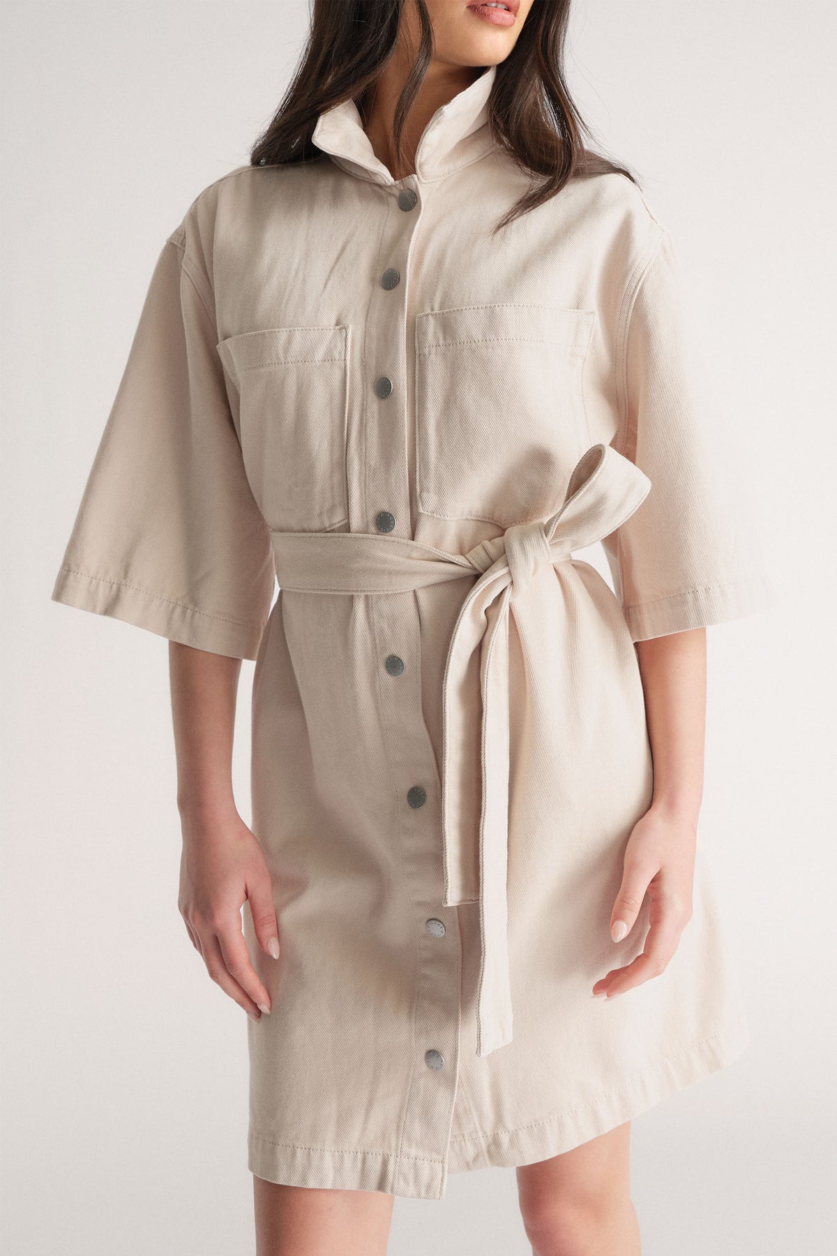D-Luxe Denim Short Dress in neutral tone with press studs, elbow sleeves, chest pockets, waist tie, portrait gallery shot 2