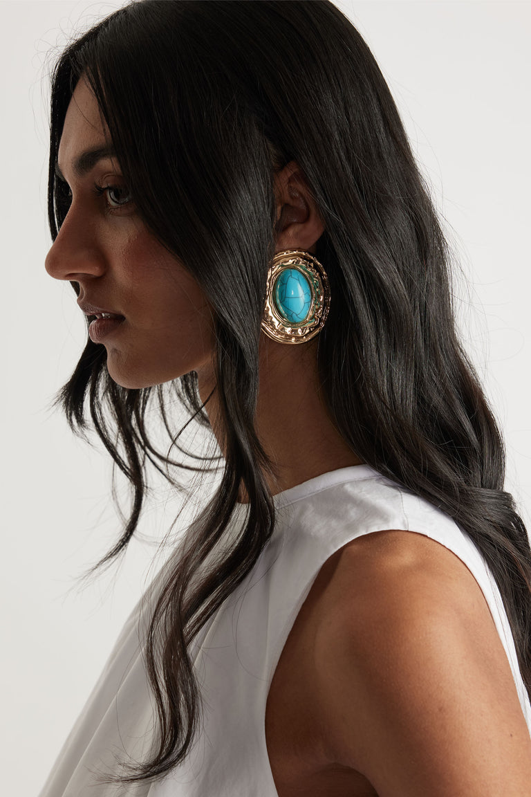 Portrait of woman wearing Piper Stone Earrings with turquoise center stone and textured gold frame, gallery position 2