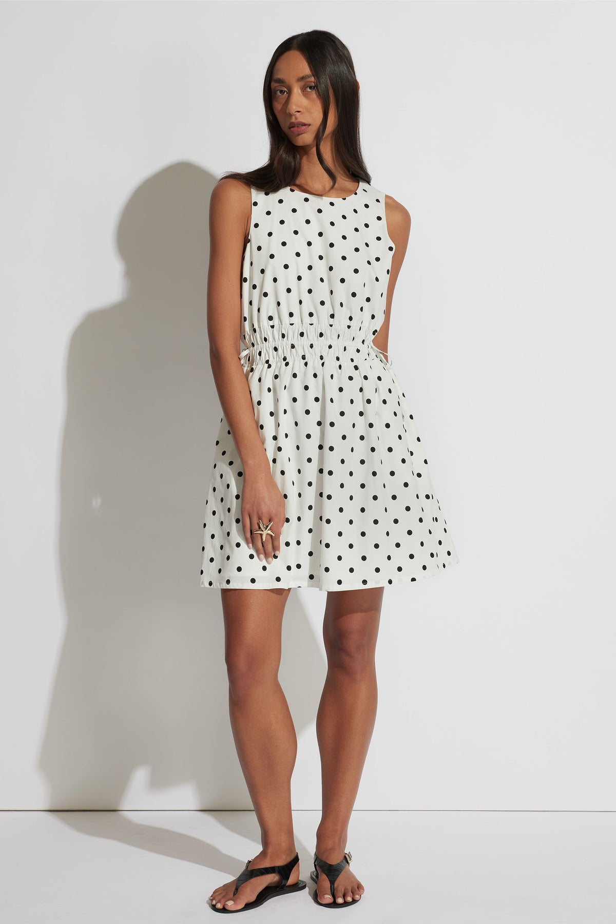 Cali Spot Mini Dress in white with black polka dots, sleeveless, shirred waist, front gallery position 1 portrait image.