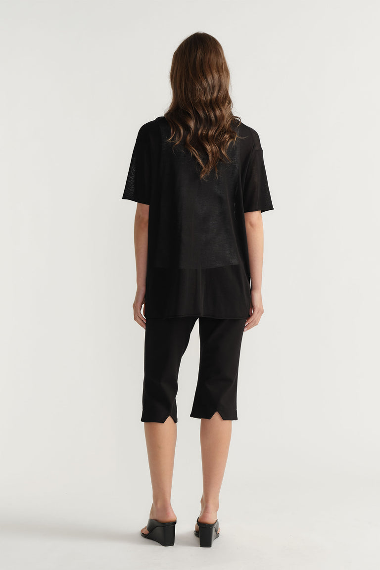 Back view of model wearing black D-Luxe Fine Knit Tee in gallery position 3 with cropped pants and heeled sandals