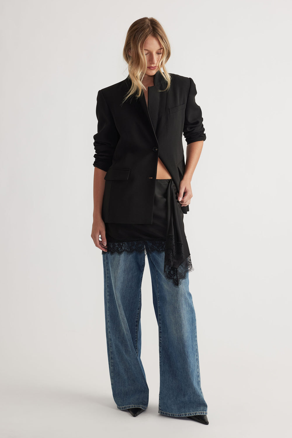 Karla Lace Mini Skirt in black satin with lace trim styled under a tailored black blazer and wide-leg denim by DECJUBA Australian brand