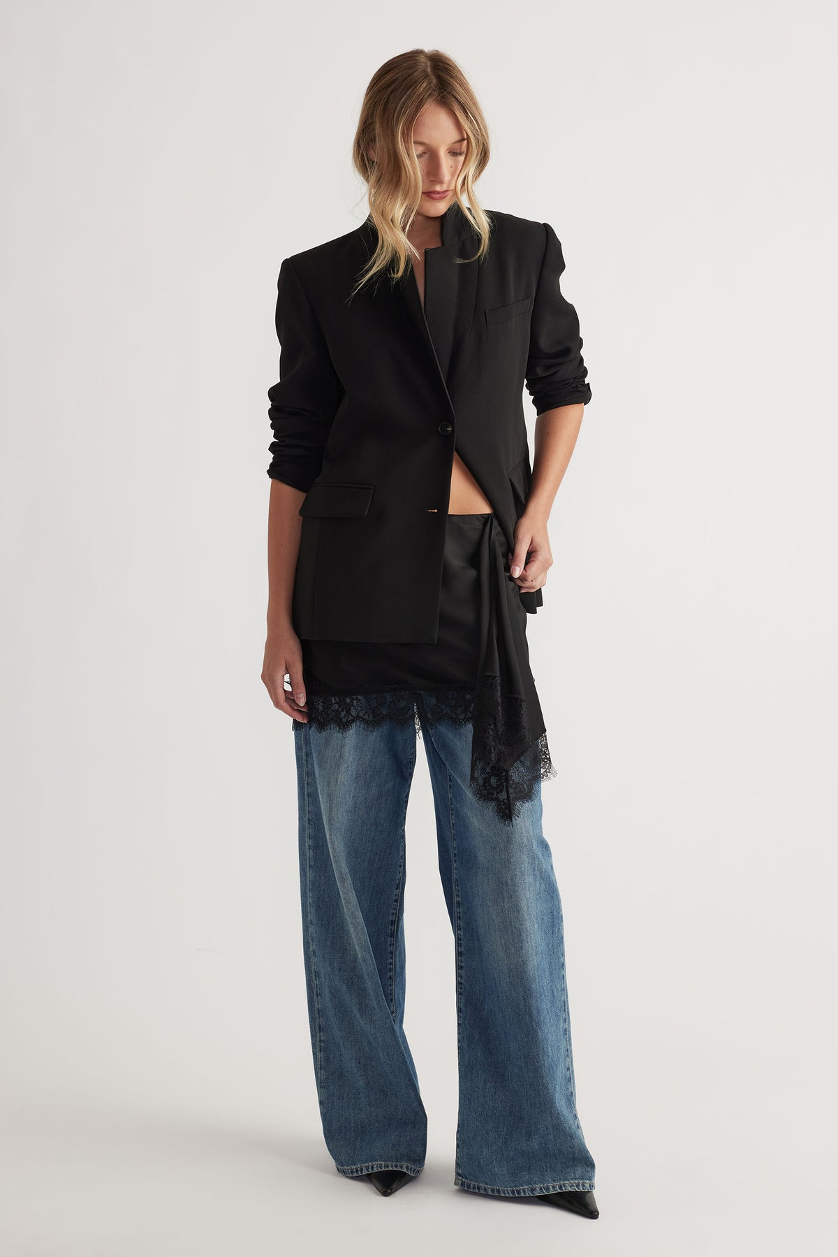 Karla Lace Mini Skirt in black satin with lace trim styled under a tailored black blazer and wide-leg denim by DECJUBA Australian brand