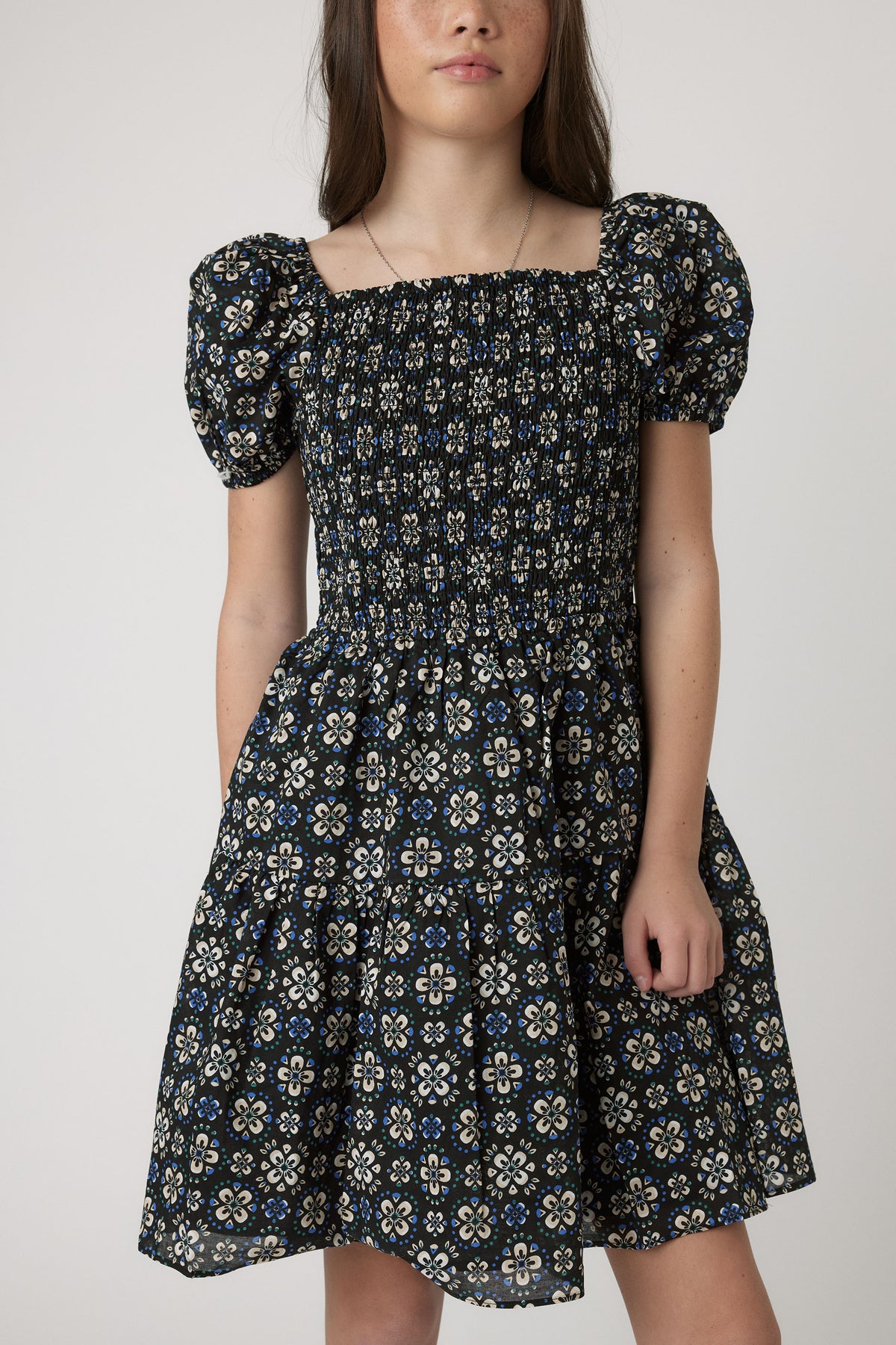 Girls Maude Mini Dress with short balloon sleeves, square neckline, elastic shirred bodice, and floral patterned skirt, portrait view.