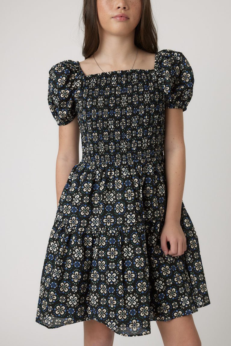 Girls Maude Mini Dress with short balloon sleeves, square neckline, elastic shirred bodice, and floral patterned skirt, portrait view.
