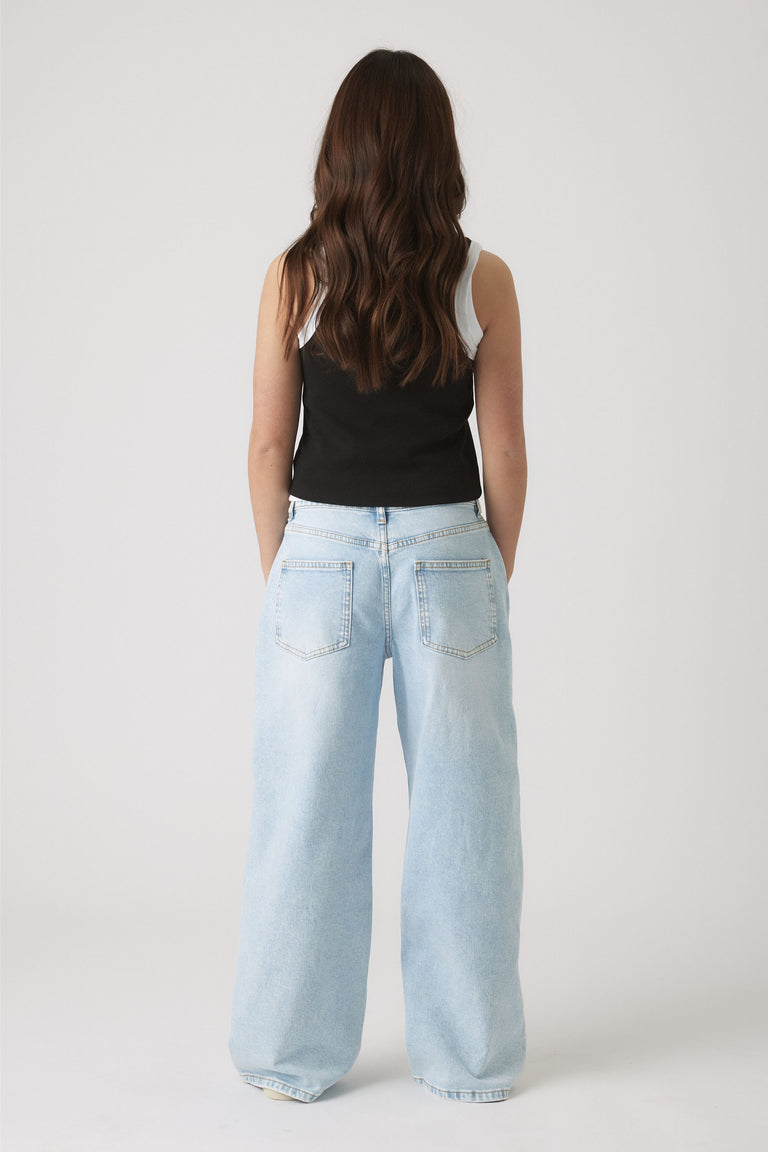 Back view of girl wearing light wash wide-leg jeans paired with a black and white layered tank top