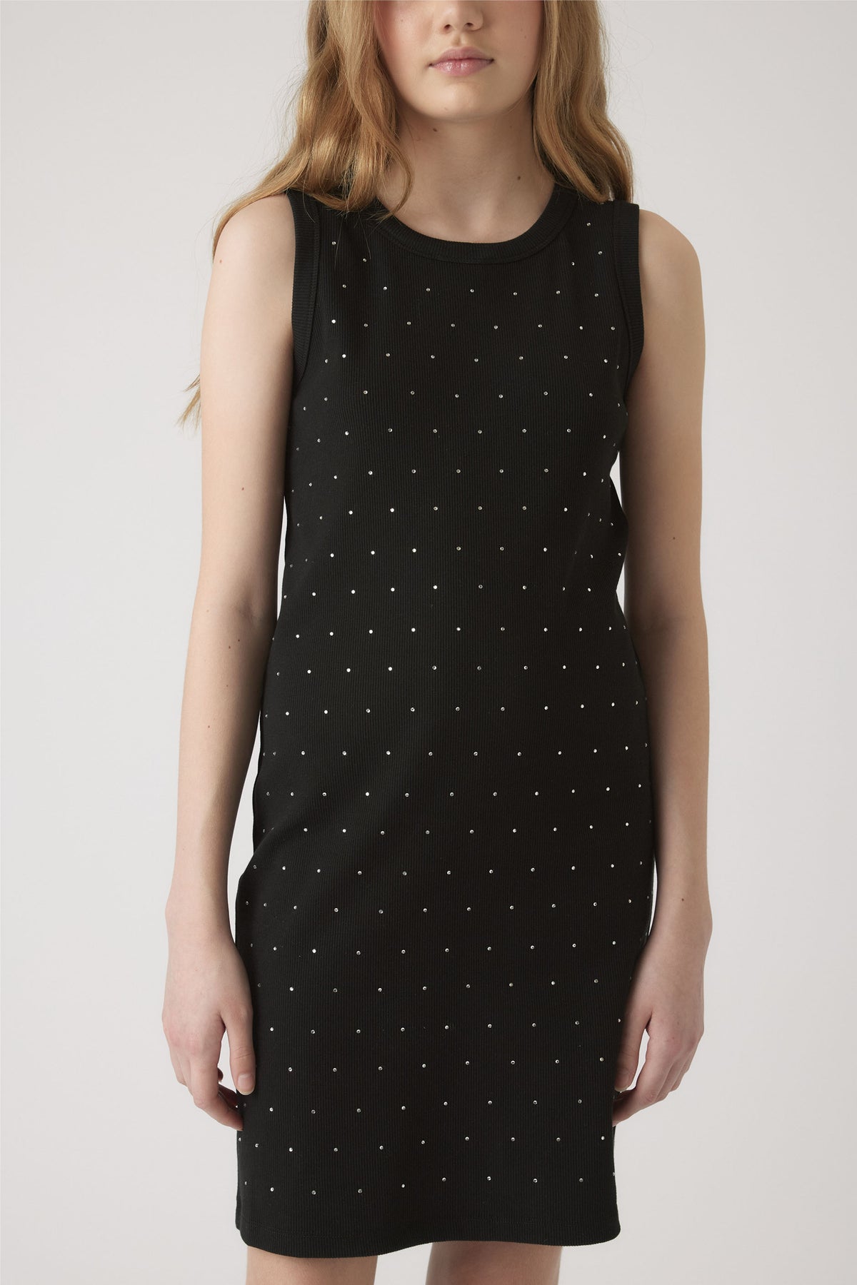 Girl wearing a sleeveless black dress adorned with small crystal accents for a subtle sparkling effect