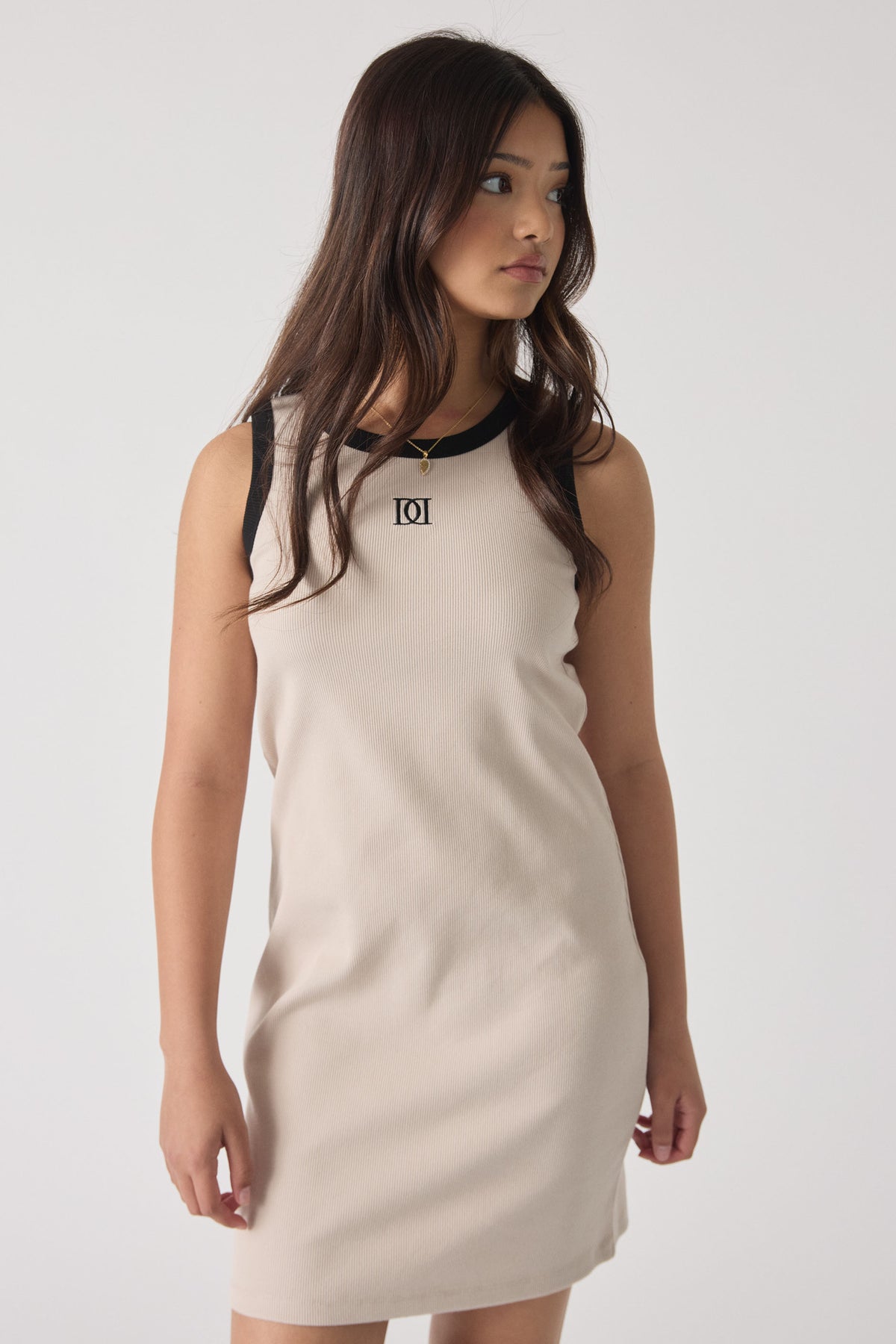 Girl wearing a sleeveless eggshell dress with black trim and monogram detail, styled for casual, effortless wear.