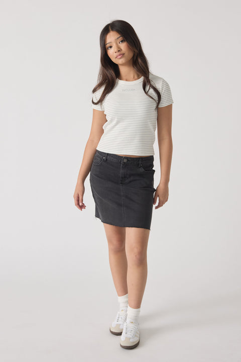 Young woman wearing a fitted striped crop tee paired with a black denim skirt and white sneakers in a casual look.
