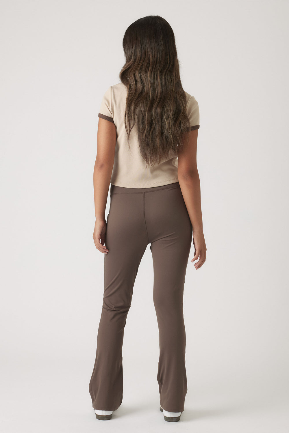 Back view of girl wearing a cropped ringer tee in beige with chocolate brown trim paired with fitted brown pants
