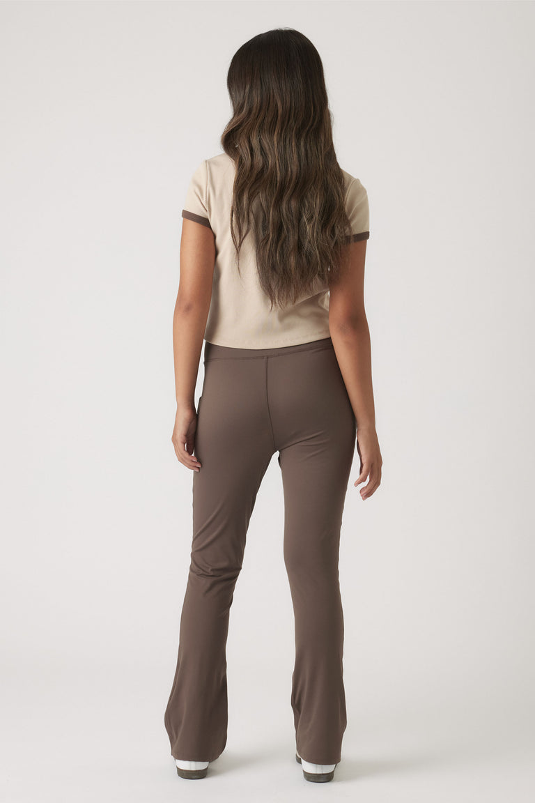 Back view of girl wearing a cropped ringer tee in beige with chocolate brown trim paired with fitted brown pants