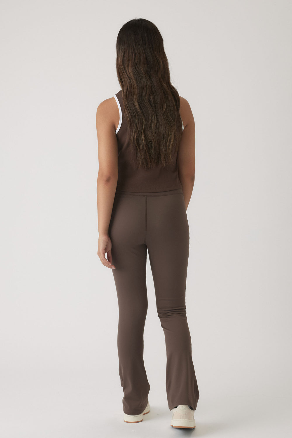 Back view of girl wearing a mocha cropped tank paired with matching fitted flared pants and white sneakers