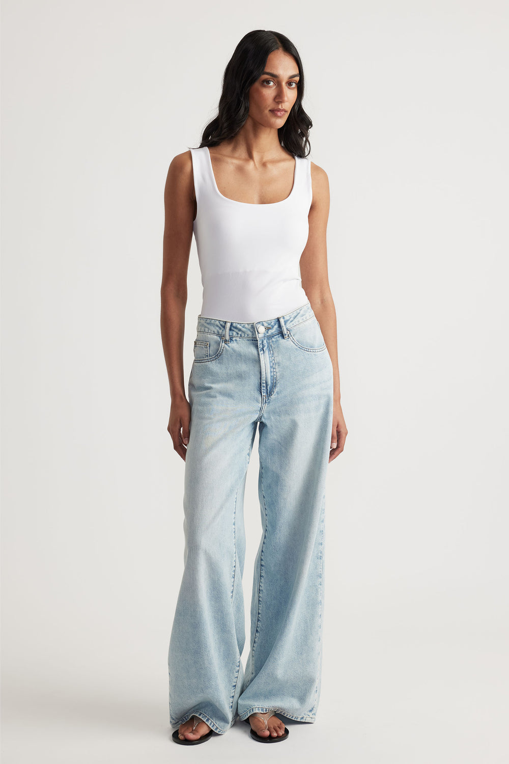 Woman wearing a white seamless scoop tank with light wash wide-leg jeans for a laid-back, versatile look.