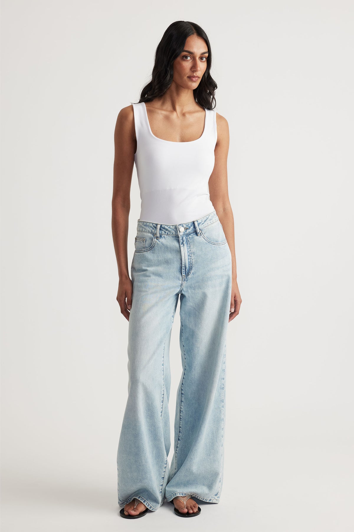 Woman wearing a white seamless scoop tank with light wash wide-leg jeans for a laid-back, versatile look.