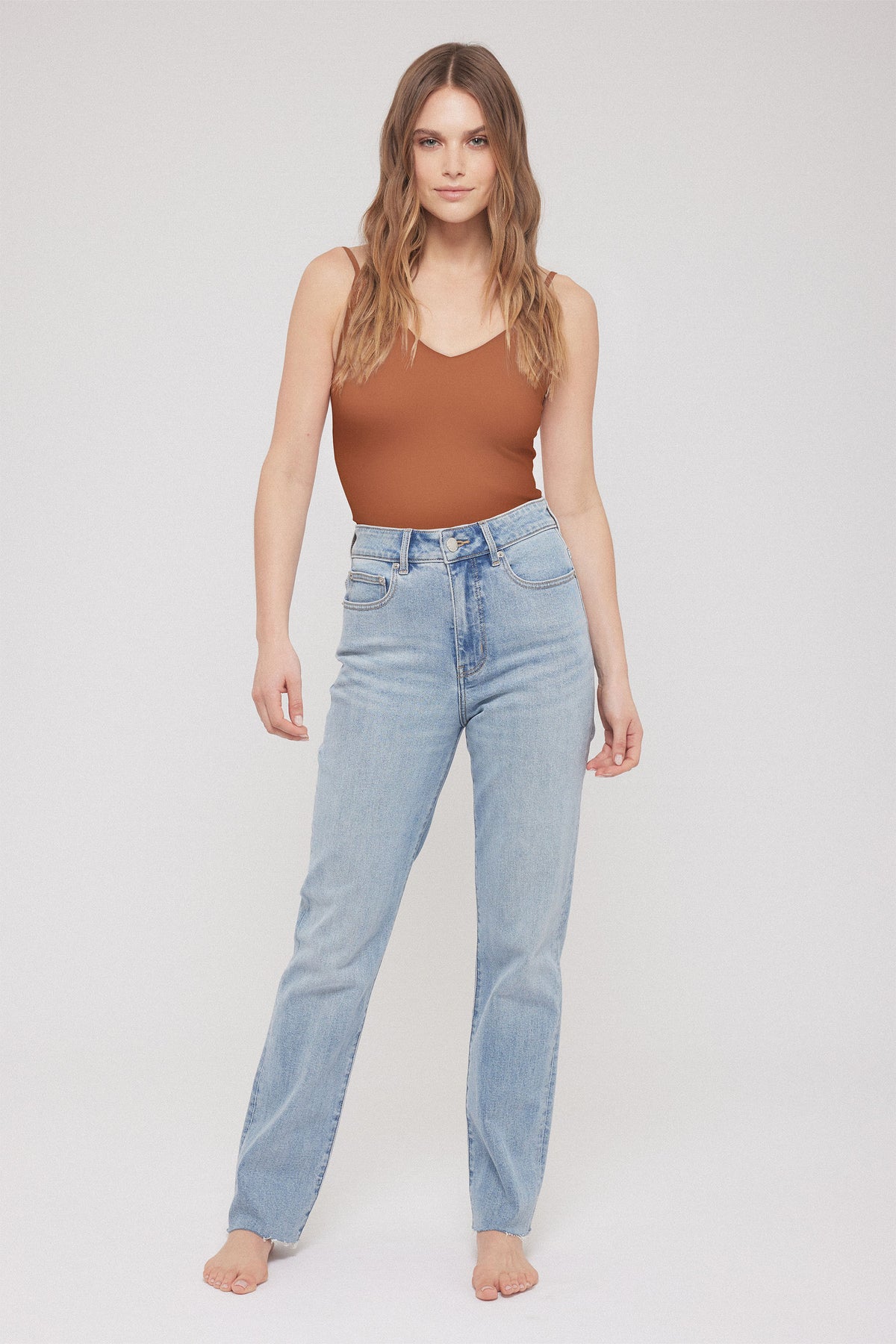 Woman modelling a brown seamless V-neck tank with light blue high-waisted jeans