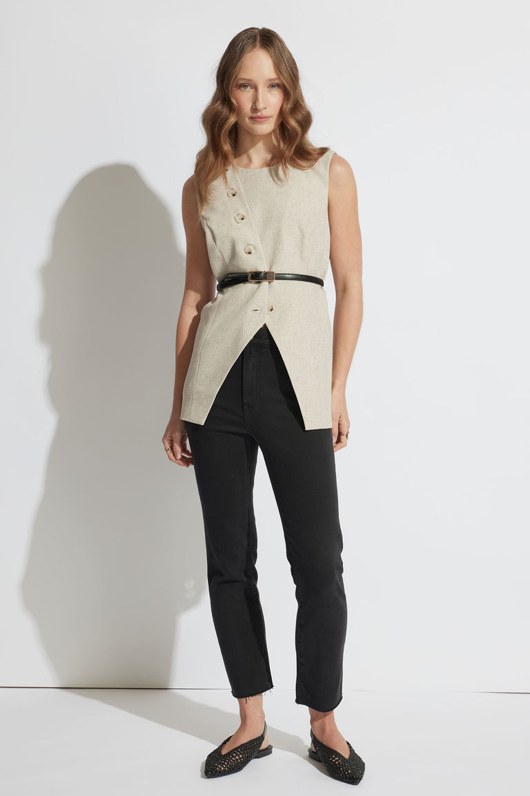 Portrait of a woman wearing black Becky Straight Leg Jean with raw hem, styled with a belted beige sleeveless top, gallery 1.