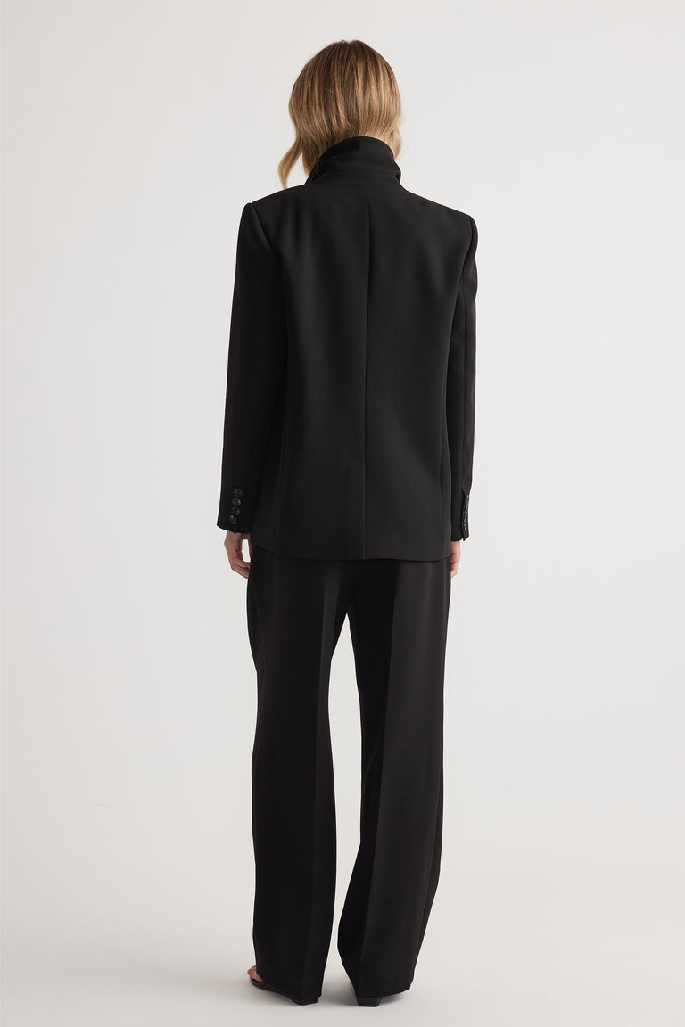 Back view of woman wearing black tailored pants with a matching blazer for a sleek, modern silhouette
