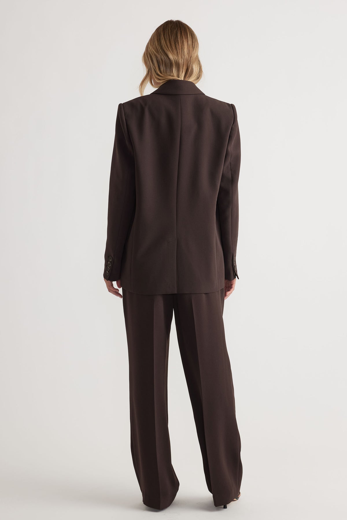Back view of woman wearing tailored dark brown pants and matching blazer for a refined, modern look