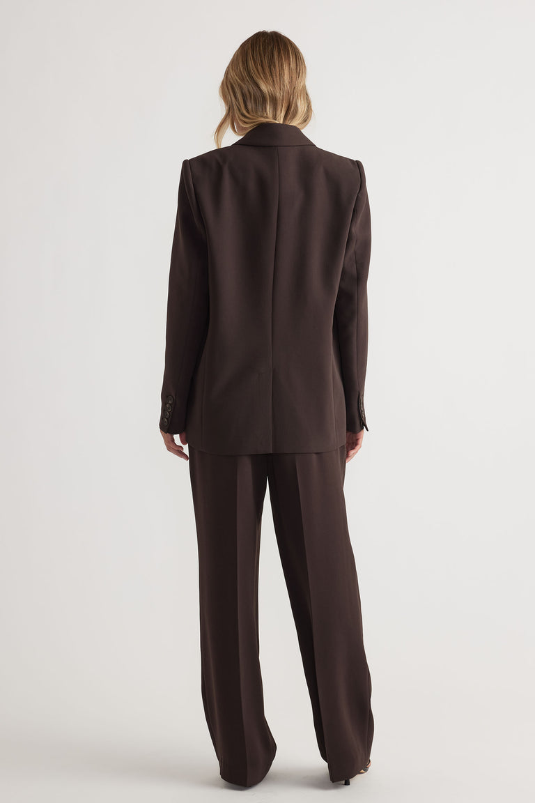 Back view of woman wearing tailored dark brown pants and matching blazer for a refined, modern look