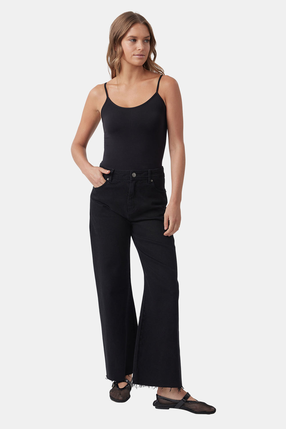 Woman wearing a black seamless thin strap tank with high-waisted wide-leg black jeans and mesh ballet flats