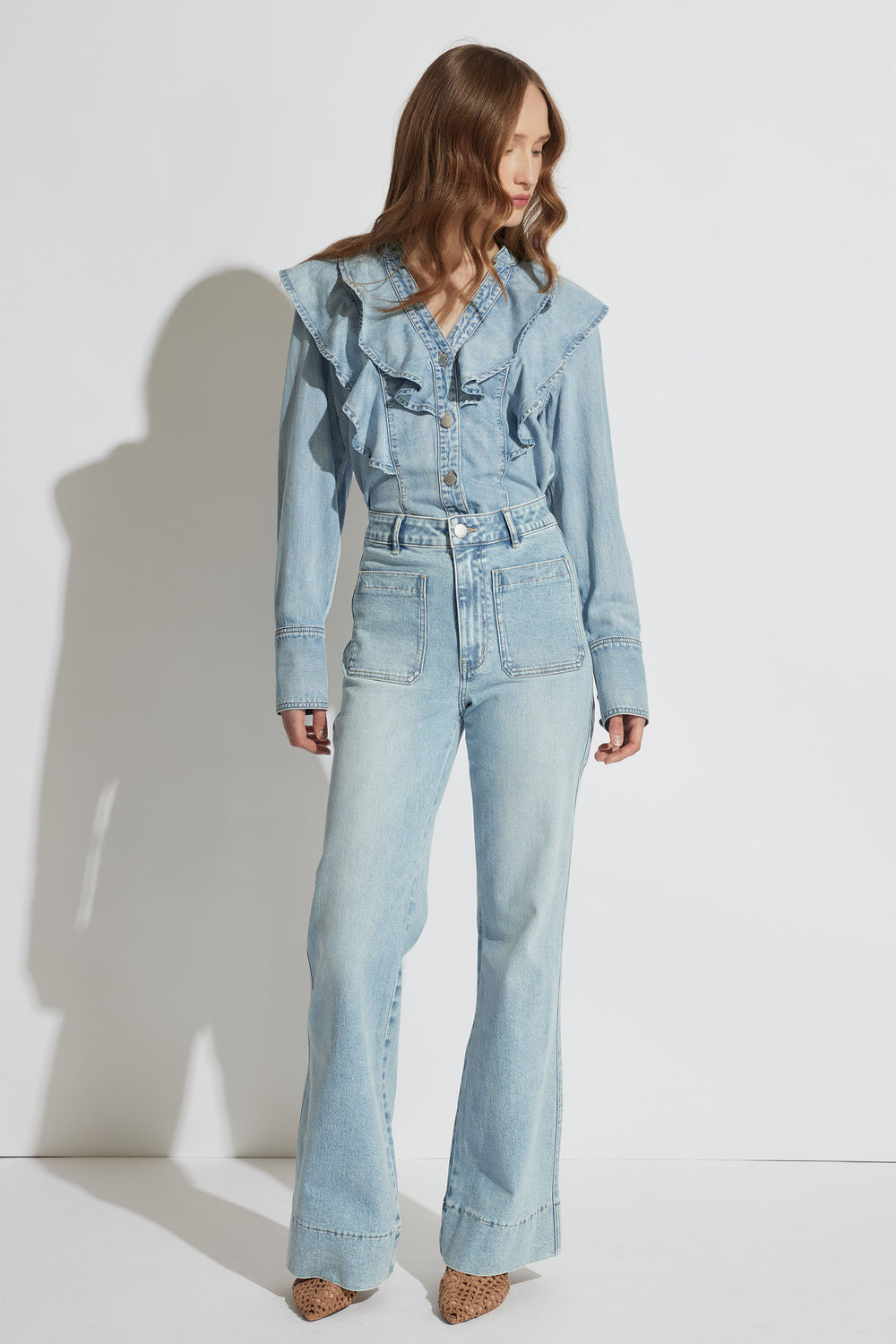 Cecilia Ruffle Denim Blouse in light wash with ruffle detail, button front, and long sleeves, styled with high-waist jeans.