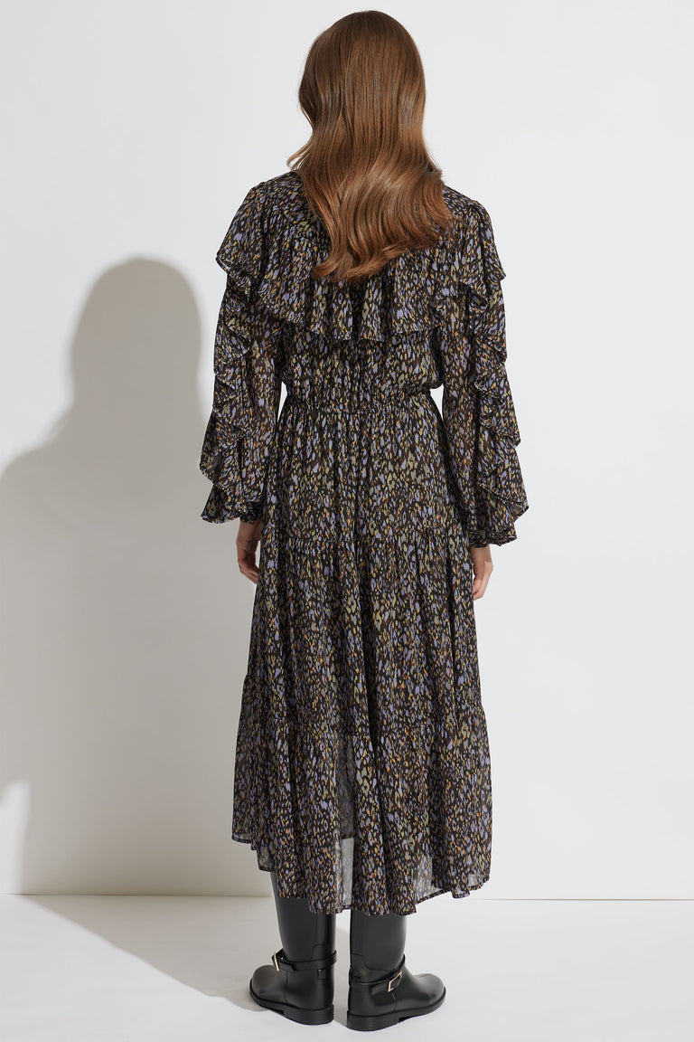 Back view of a woman wearing a dark floral midi dress with ruffles and long sleeves, paired with black boots.