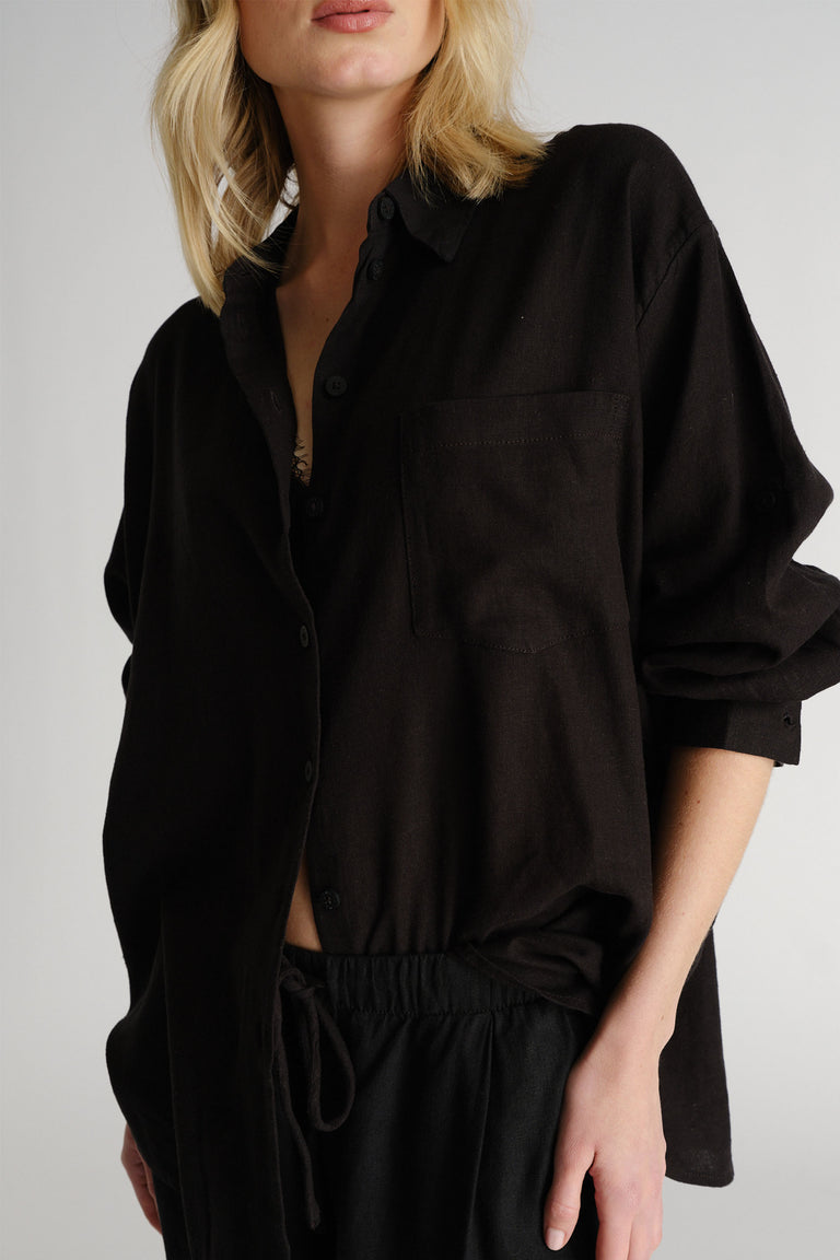 Portrait of a woman wearing a black D-Luxe Linen Blend LS Shirt, showcasing its relaxed fit and soft linen fabric.
