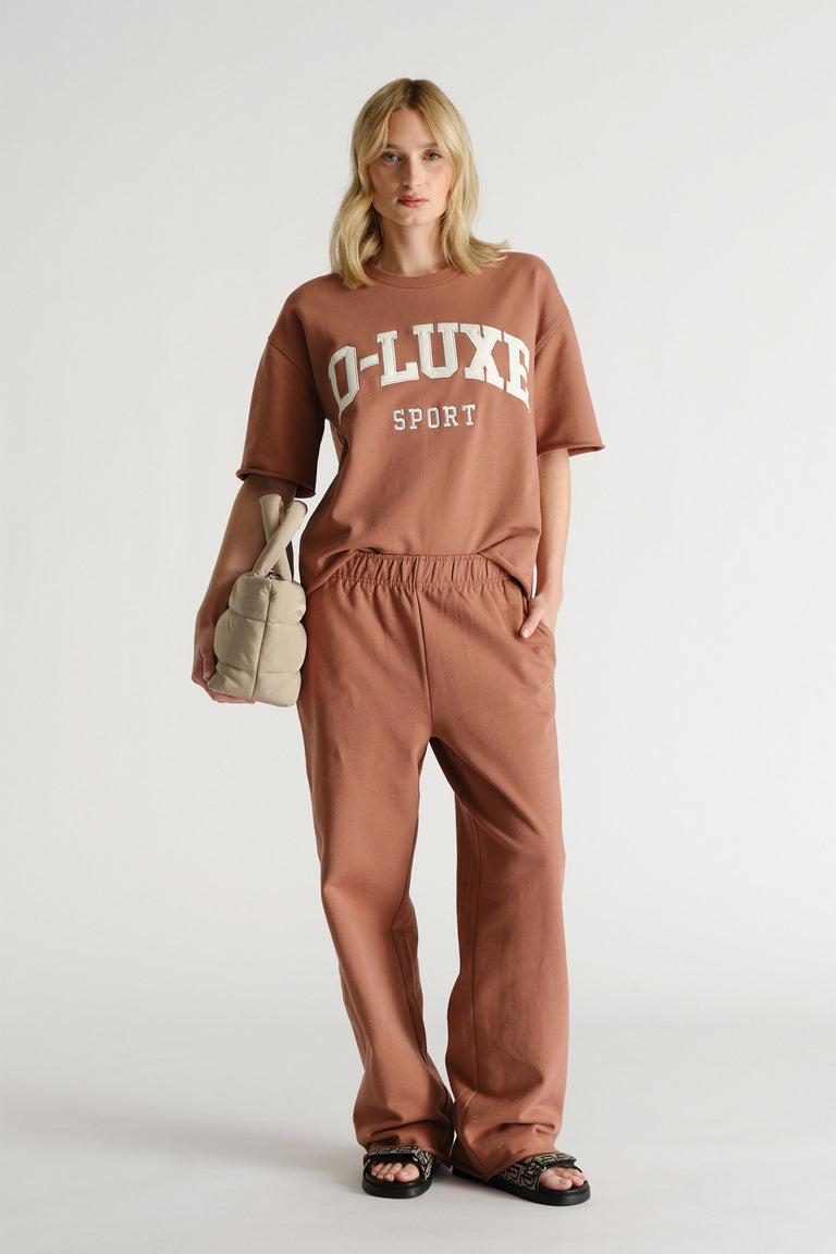 Woman wearing brown high waisted wide leg track pants with an elastic waist and side pockets