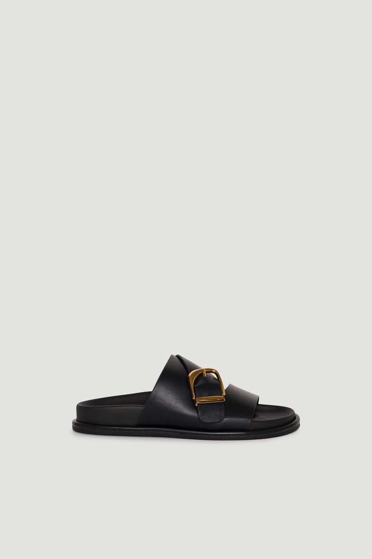 Black slide sandal featuring a wide strap with gold buckle detail and a comfortable flat sole design.