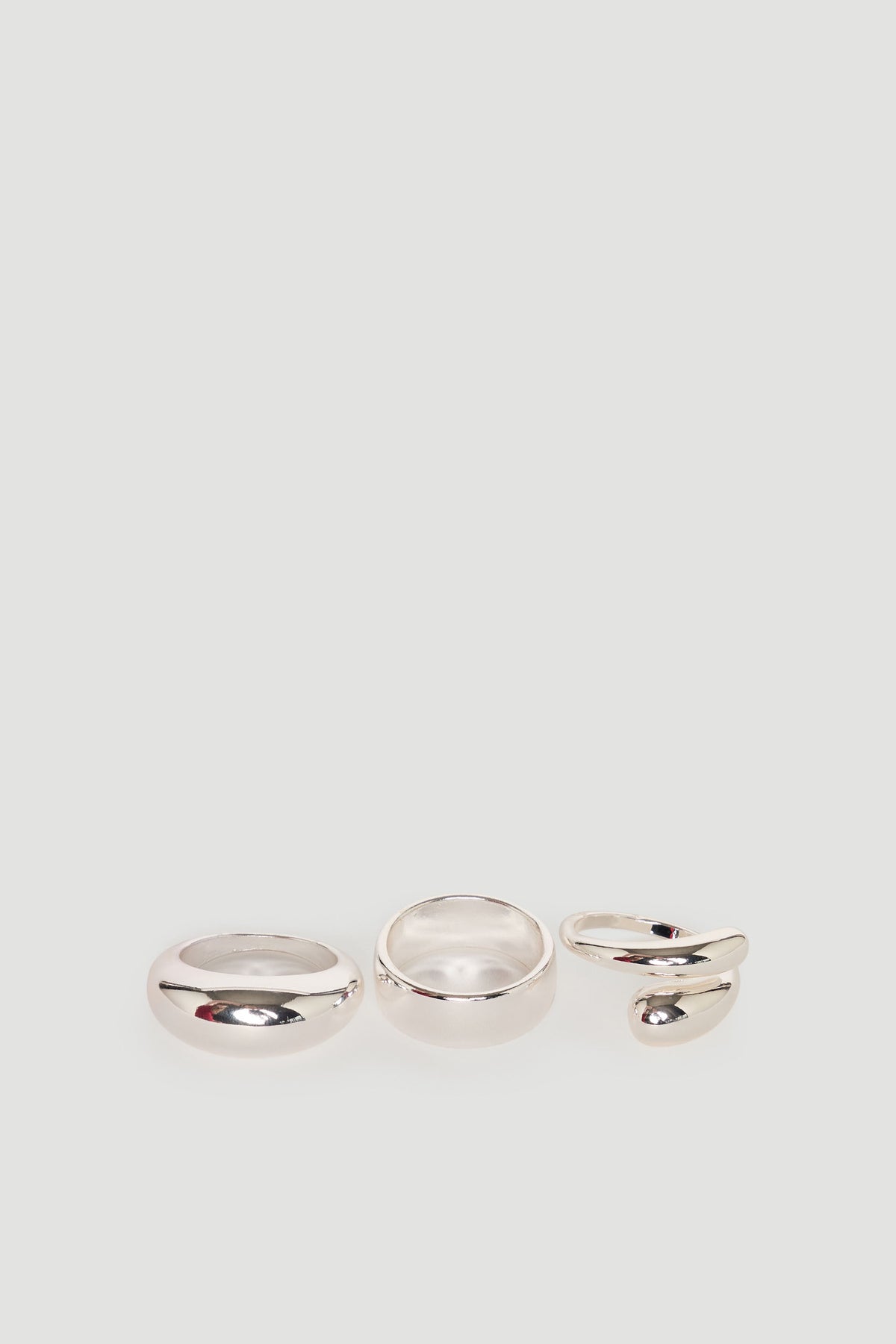 Set of three polished silver rings including a classic band, a wider band, and an open swirl design ring.